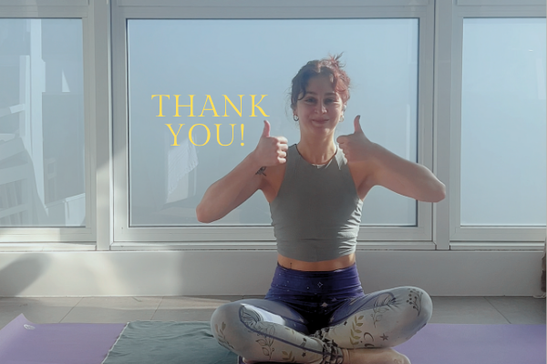A woman doing thumbs up in yoga pants on a yoga mat.