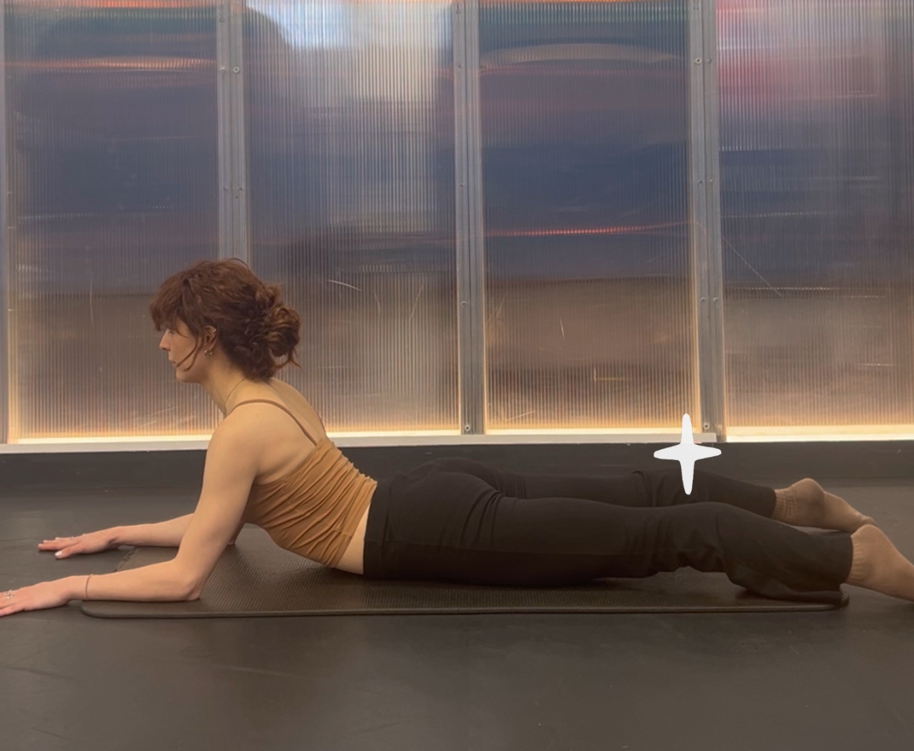 A woman showing how to perform Sphinx pose with her legs engaged