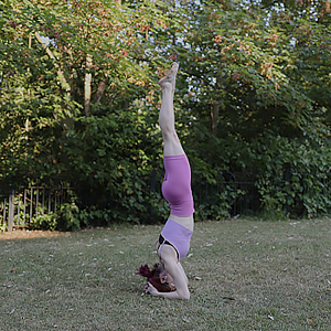 A woman in a headstand position at a park.